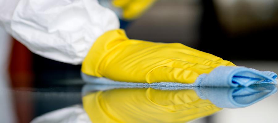 a gloved hand wipes off a table